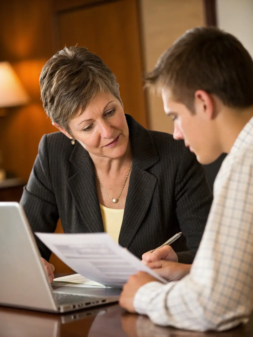 A friendly insurance agent sitting across a table, explaining policy details to a client with a warm smile, emphasizing personalized service.